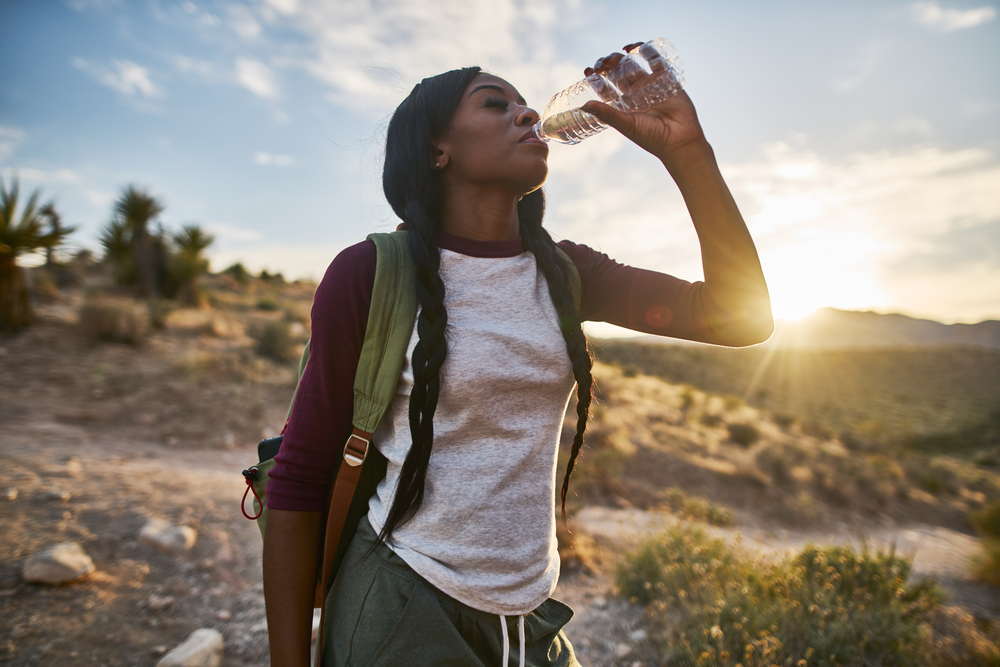 woman drinking water in the desert while hiking