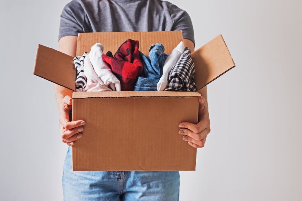 person holding out open box full of clothes