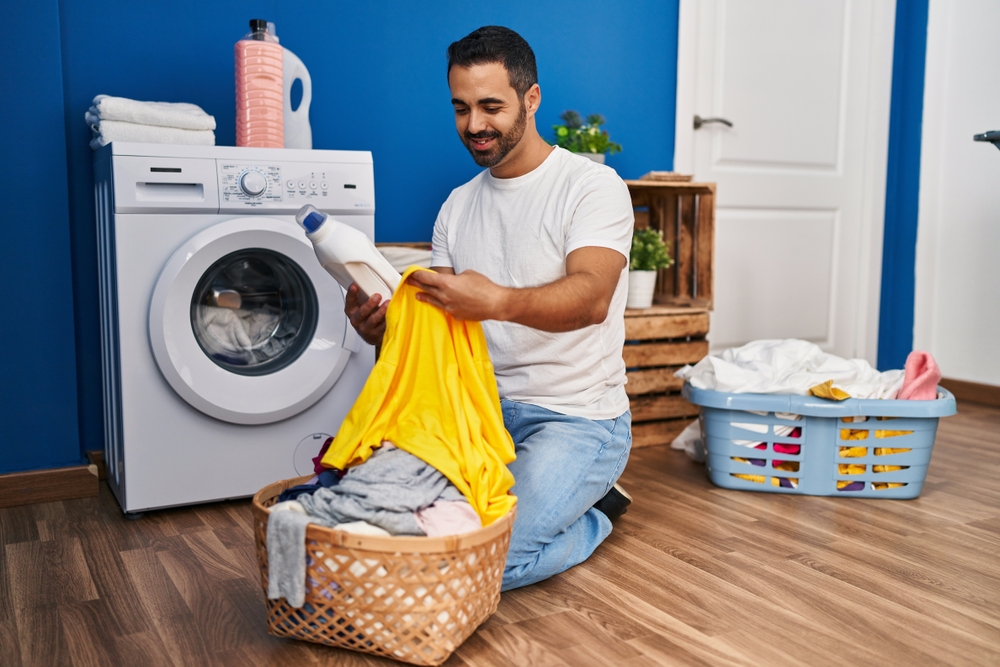 Man looking at detergent and holding up some clothes