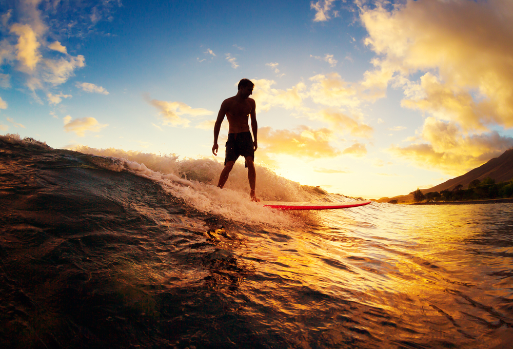 Young person on a surfboard at sunset