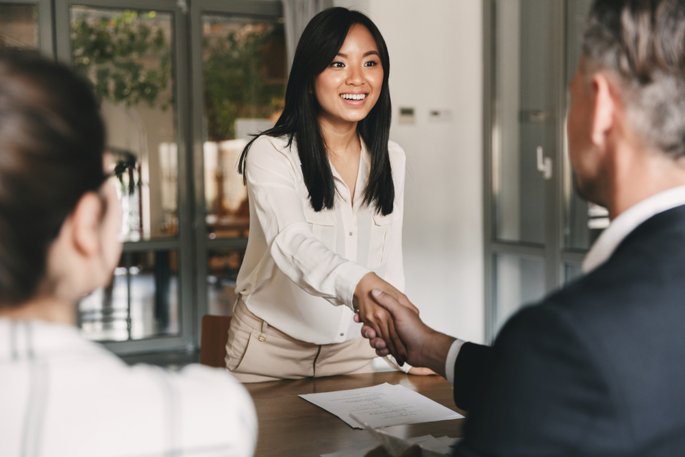 Woman shaking hands with two business people