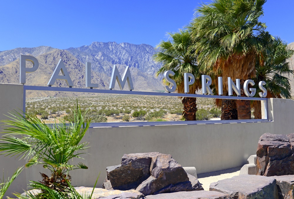 Palm Springs sign with palm trees and desert in the background